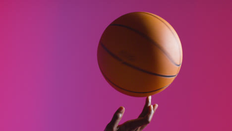 Close-Up-Studio-Shot-Of-Male-Basketball-Player-Spinning-Ball-On-Finger-Against-Pink-Lit-Background-2